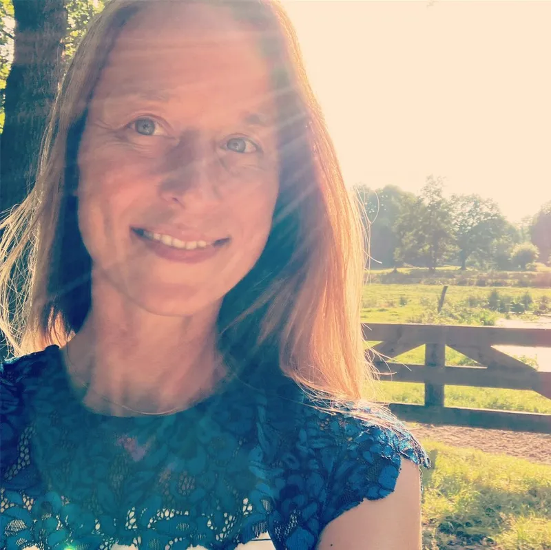 Iris lacht in de zon, met een weiland en bomen op de achtergrond
